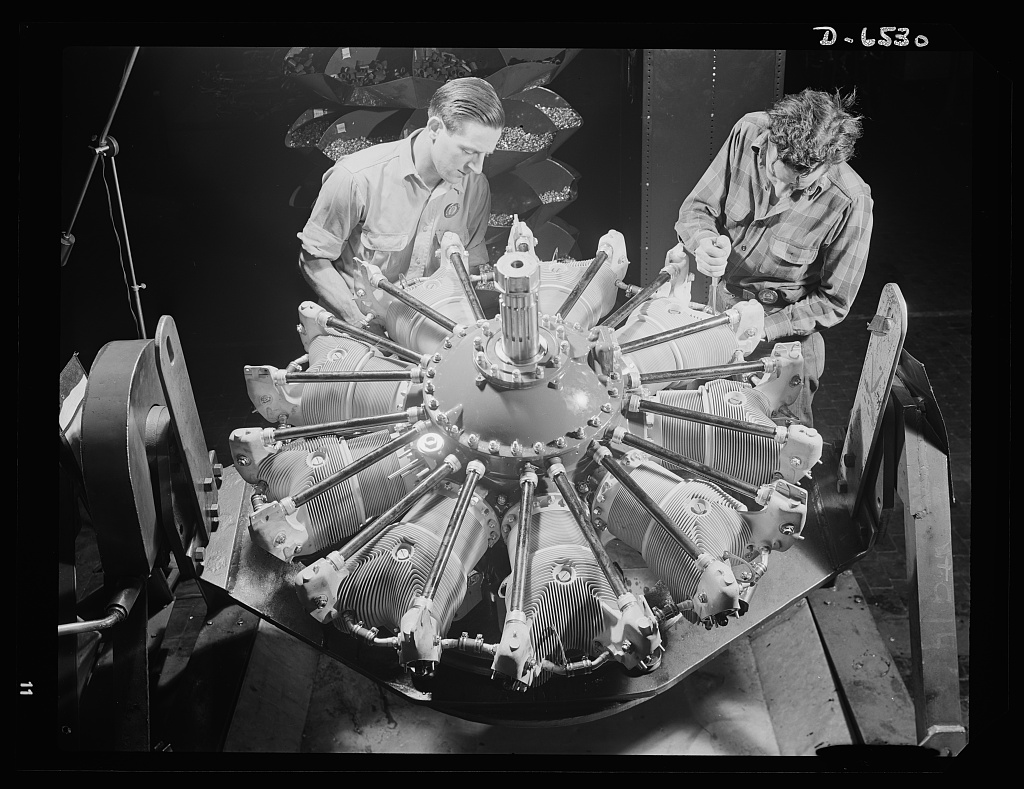 Two men installing single-row intake pipes on a Pratt and Whitney radial airplane engine, East Hartford, June 1942.