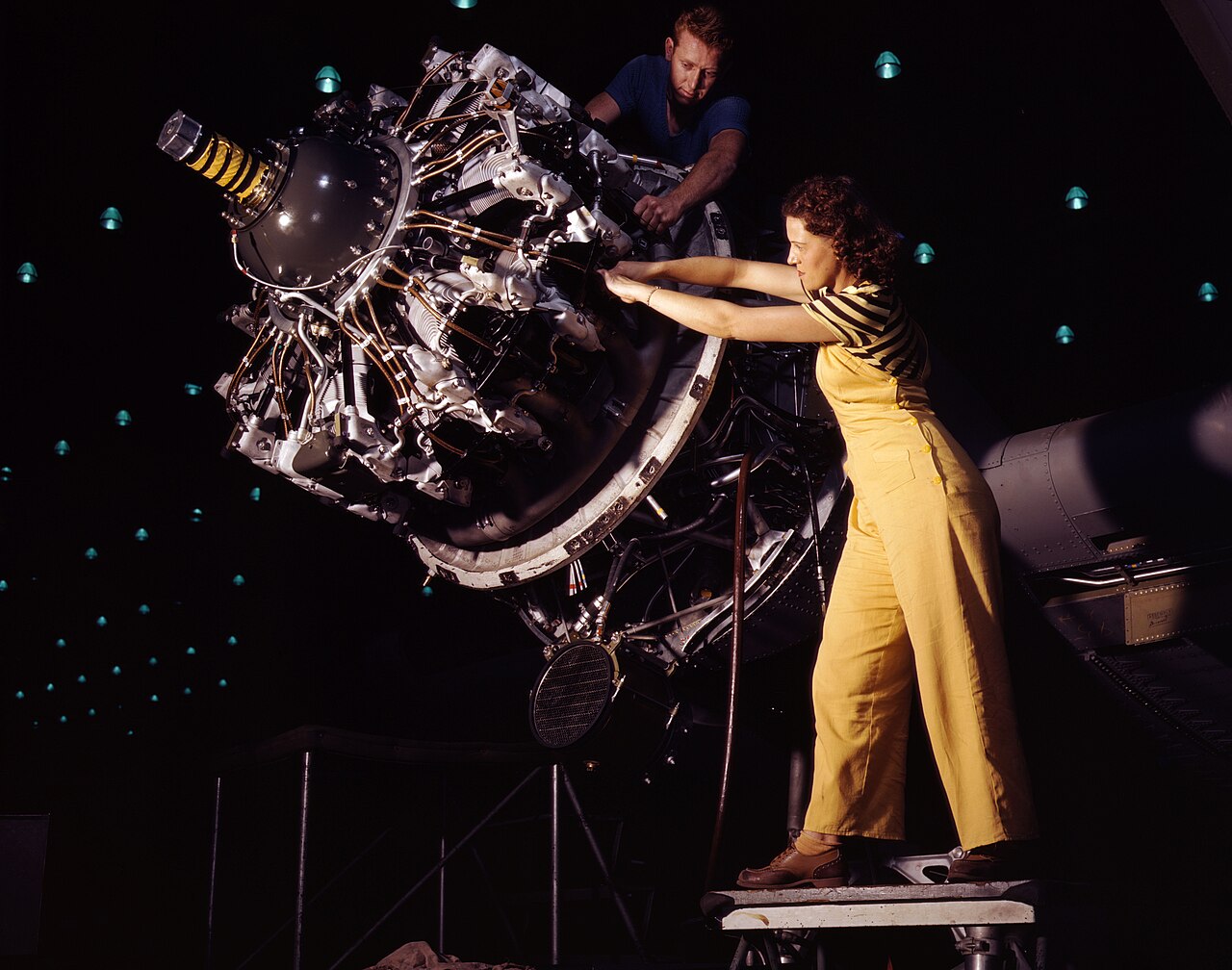 A woman and a man installing a Pratt and Whitney R-1830 Twin Wasp radial engine on a Douglas C-47 at the Long Beach factory, October 1942.
